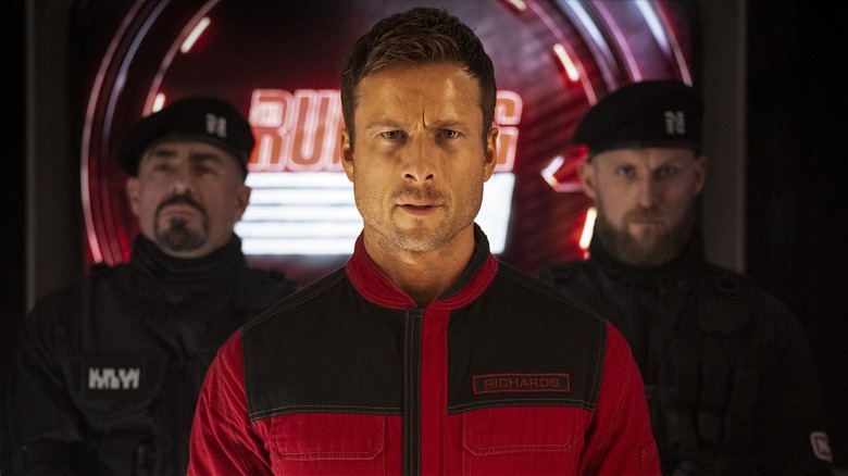 Ben Richards debout, flanqué de gardes