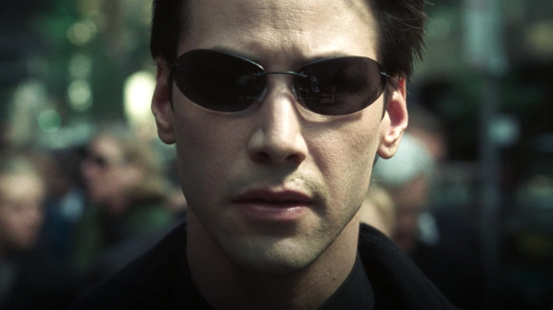Keanu Reeves dans le rôle de Neo portant des lunettes de soleil dans The Matrix