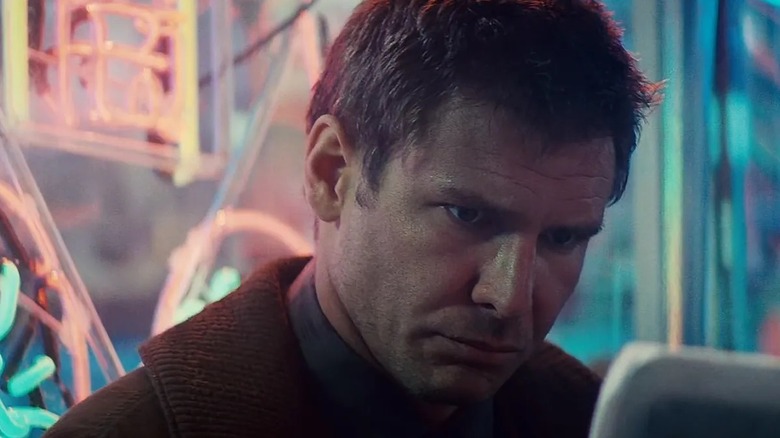 Deckard à côté de quelques enseignes lumineuses dans Blade Runner (1982)