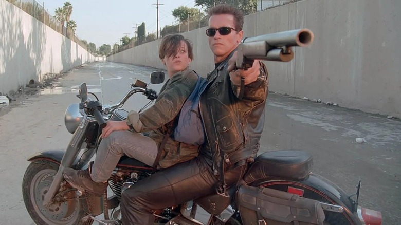 Le T-800 visant un fusil de chasse avec John Conner sur sa moto dans Terminator 2 : Judgment Day