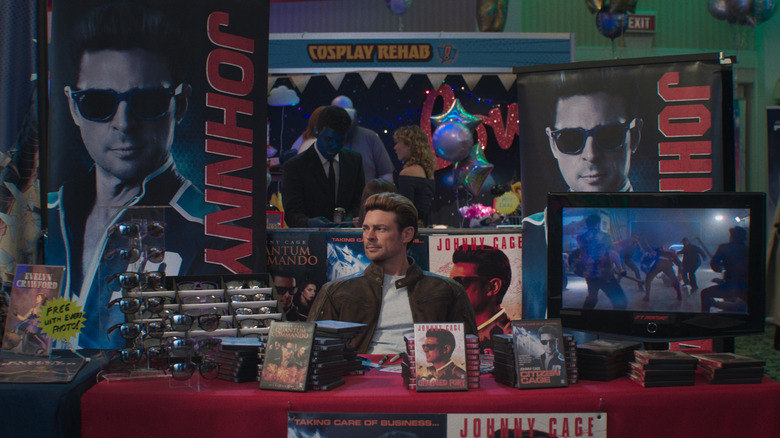 Johnny Cage assis à une table de produits dérivés dans Mortal Kombat II (2026)