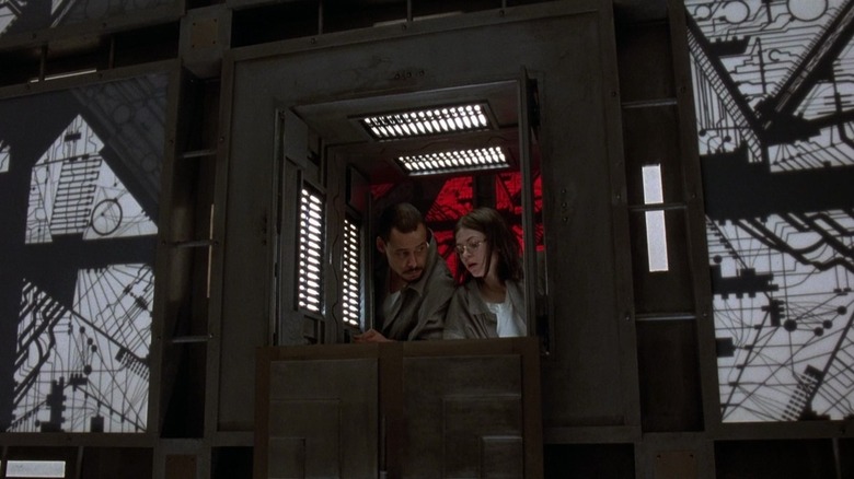 Quentin et Joan dans Cube regardent d'une pièce rouge vers une pièce blanche