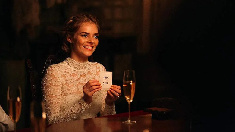 Grace souriant et tenant la carte de cache-cache dans Prêt ou pas