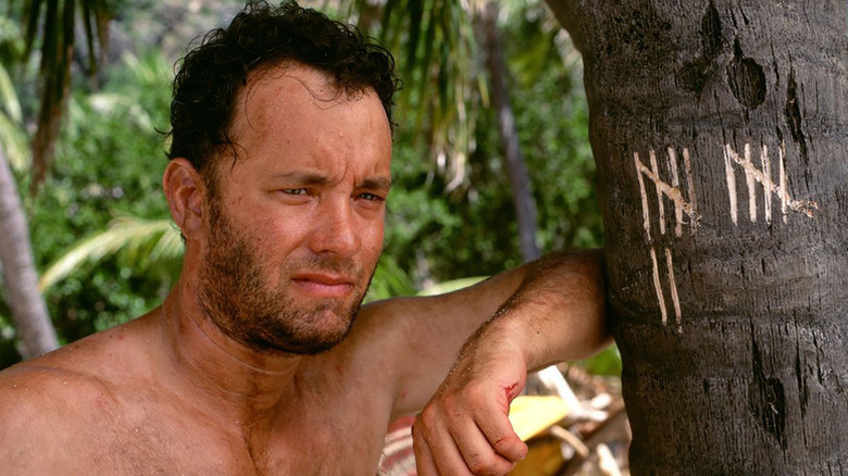 Chuck debout à côté d'un arbre avec des encoches dans Cast Away