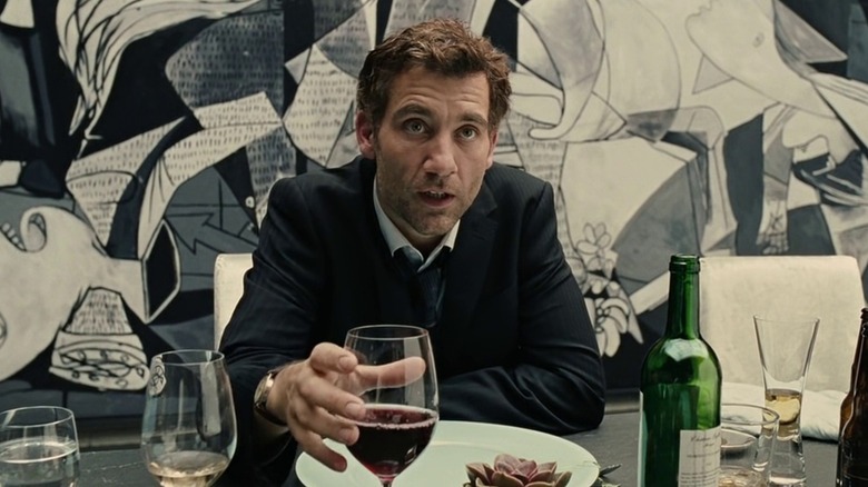 Théo tient un verre de vin assis devant Guernica de Picasso à "Enfants des hommes"