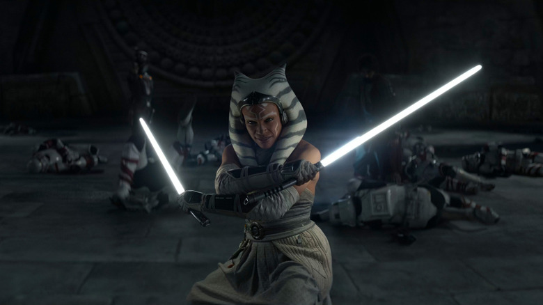 Ahsoka brandissant deux sabres laser blancs, corps de Stormtroopers derrière elle au sol, dans Ahsoka (2023)