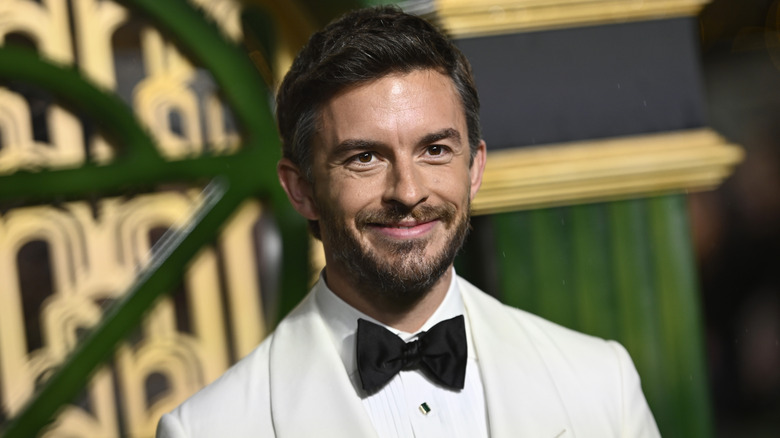 Gros plan de l'acteur Jonathan Bailey posant lors de la première de Wicked dans un smoking blanc