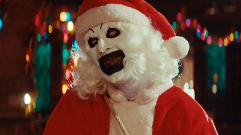 Art the Clown terrifiant le Père Noël d'un centre commercial avec un souffleur de feuilles dans Terrifier 3