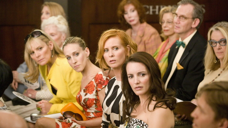 Les protagonistes de Sex and the City se retournent sous le choc lors d'une vente aux enchères dans Sex and the City (2008)
