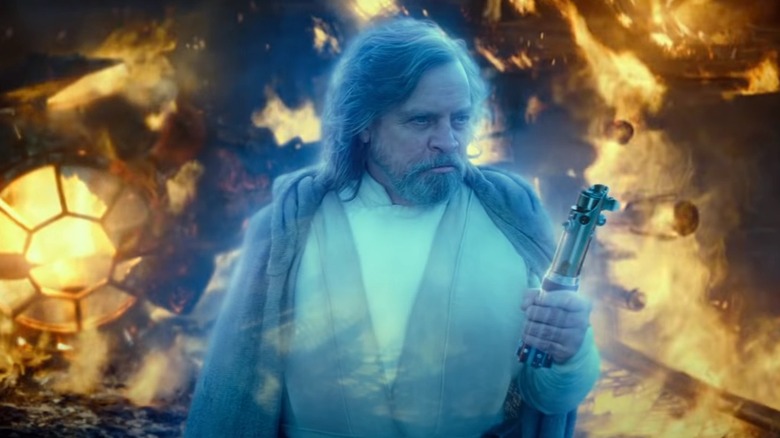 L'Esprit de Force de Luke Skywalker tenant un sabre laser au milieu de l'épave du vaisseau spatial 