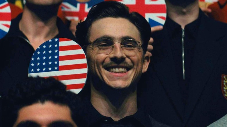 Marty brandissant une pagaie avec le drapeau américain dans Marty Supreme