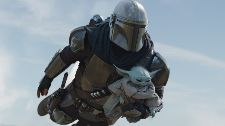 Din Djarin portant Grogu alors qu'il vole dans The Mandalorian et Grogu