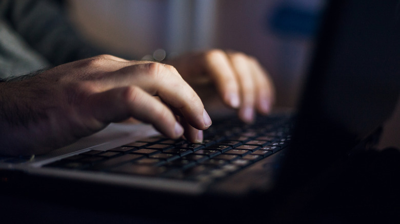 Un homme tapant sur un ordinateur portable la nuit