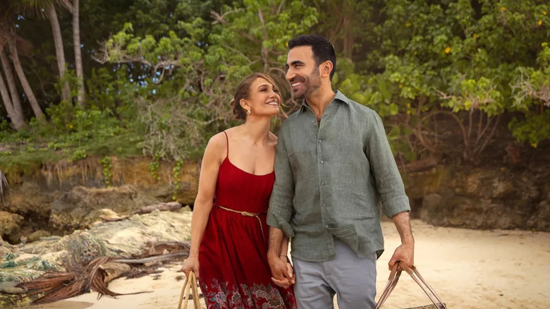 Jackie et Daniel se tiennent la main ensemble sur une plage dans Office Romance