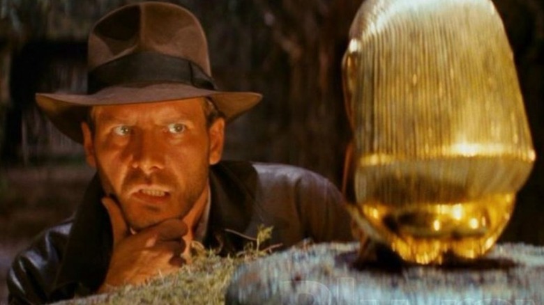 Indiana Jones examinant une statue dorée dans Les Aventuriers de l'arche perdue (1981)