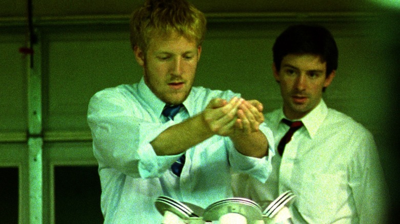 Adam regarde Aaron mettre la main sur la machine dans Primer (2004)