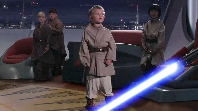 Les Jedi Younglings se tiennent devant Dark Vador qui a allumé son sabre laser 
