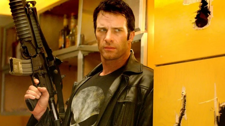 Frank Castle se tient contre un mur avec une arme levée 