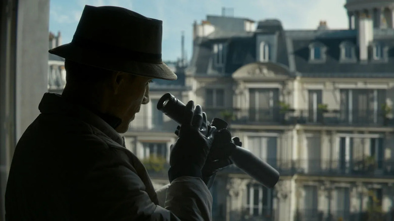 Le Tueur regarde à travers un pistolet télescope dans The Killer