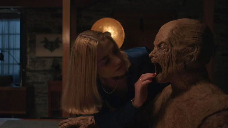 Yana enquête sur la bouche d'un personnage en bois dans Oddity