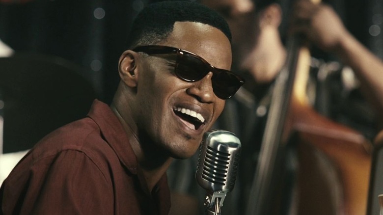 Ray portant des lunettes de soleil chantant dans un microphone dans Ray (2004)