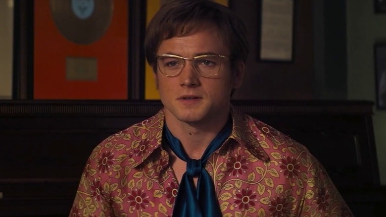 Elton dans une chemise à imprimé floral et une cravate bleue dans Rocketman (2019)