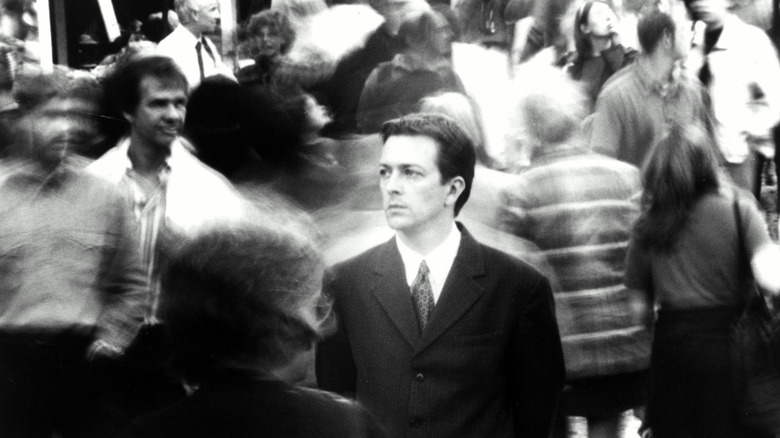 Le jeune homme debout au milieu d’une foule floue 