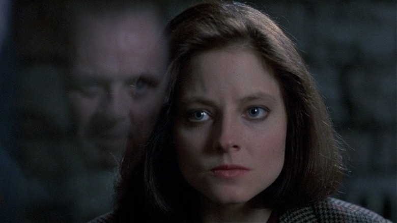 Clarice regarde Hannibal à travers une vitre. 