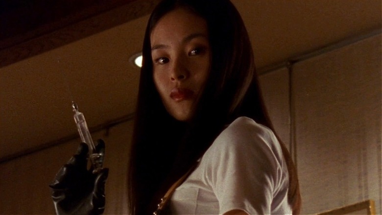 Asami baissant les yeux et tenant une aiguille dedans 