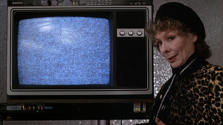 Masha debout devant une télévision avec un écran statique 