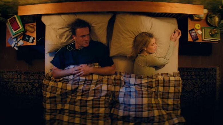 Dan et Lisa au lit avec des écouteurs dans Over Your Dead Body
