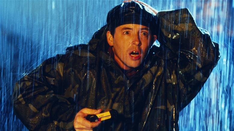 Le Dr Niko Tatopoulos a l'air effrayé en tenant son appareil photo sous la pluie