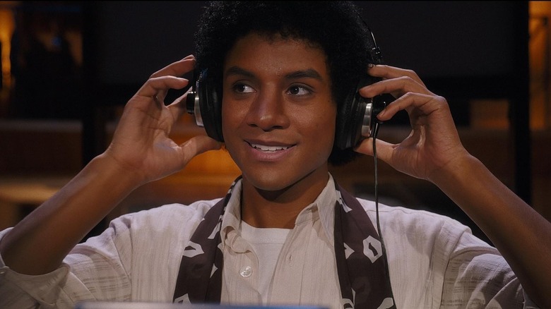 Michael souriant et ajustant ses écouteurs dans Michael (2026)