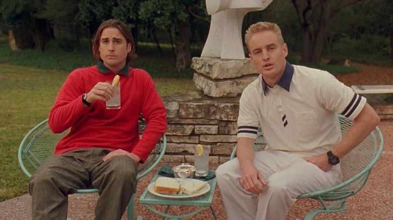 Anthony Adams et Dignan assis sur des chaises de jardin en métal