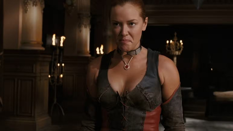 Rayne fait une grimace malheureuse dans une pièce sombre avec des bougies