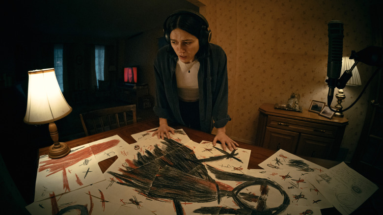Evy regarde des dessins effrayants sur la table de sa salle à manger. 