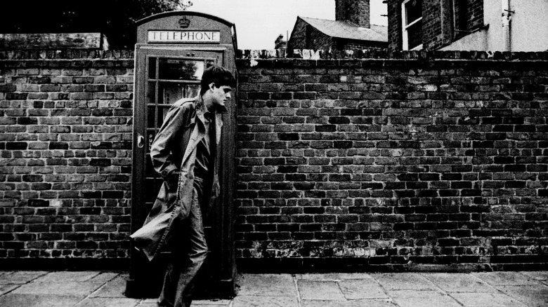Ian Curtis passant devant une cabine téléphonique 