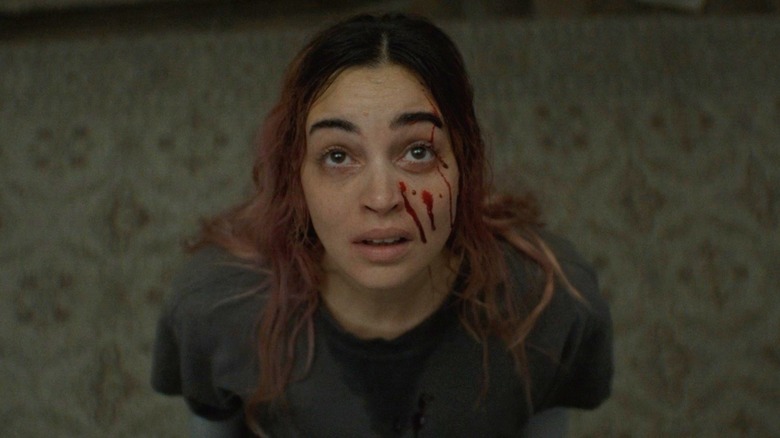 Alice levant les yeux avec des gouttes de sang sur le visage dans Evil Dead Burn (2026)