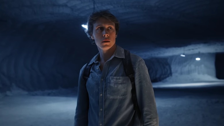 Fils marchant dans la grotte souterraine gelée où vit sa famille dans The End