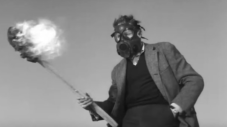 Le Dr Robert Morgan tient une torche tout en portant un masque à gaz 