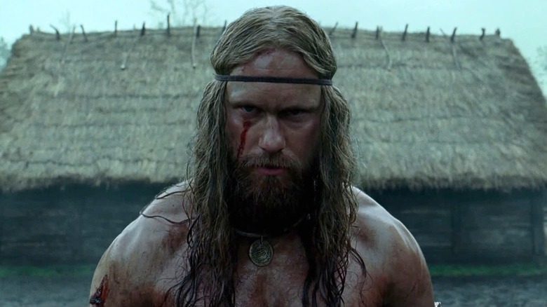 Amleth à côté d'une maison au toit de chaume dans The Northman (2022)