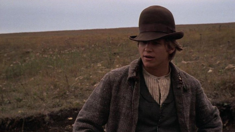 Jake Rumsey se tient dans une crevasse et porte un grand chapeau bombé dans Bad Company (1972)