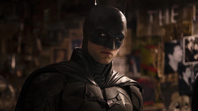 Batman debout à côté d'un mur d'images dans