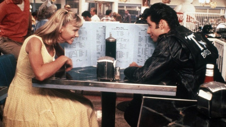 Sandy Olsson et Danny Zuko se cachent derrière les menus du restaurant de Grease