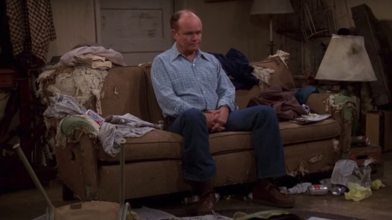 Red Foreman sur un canapé cassé