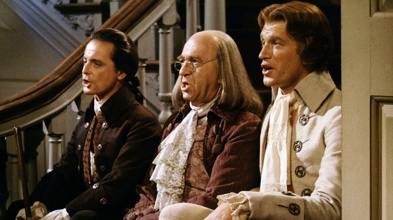 John Adams, Ben Franklin et Thomas Jefferson assis dans un escalier chantant dans 