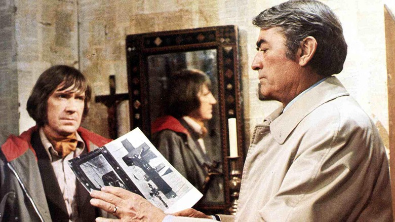 Gregory Peck tenant un livre pendant que David Warner regarde 