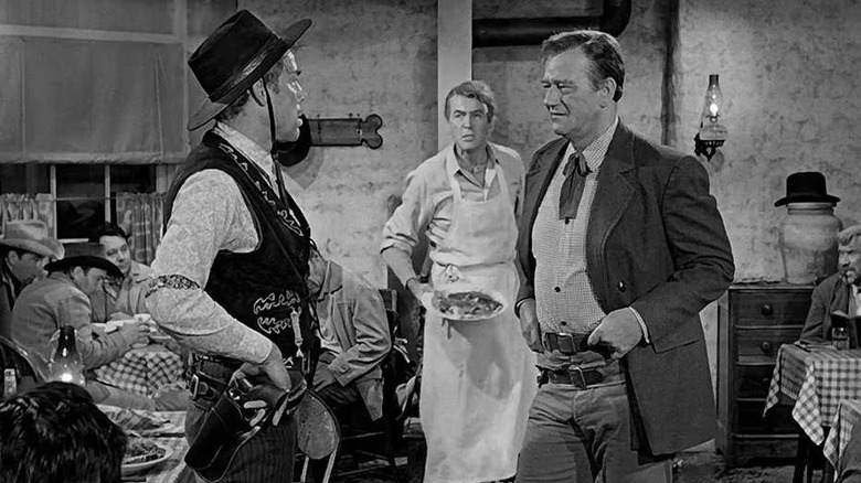 Liberty Valance affronte Tom Doniphon tandis que Ranse Stoddard regarde 