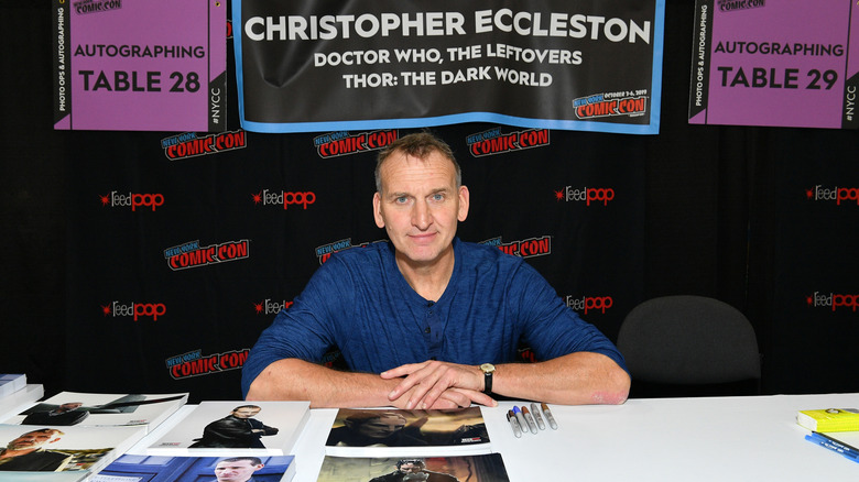 Eccleston est assis à une table