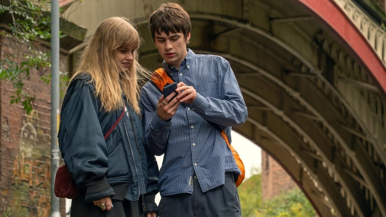 Emily regarde le téléphone d'Owen alors qu'il reçoit un SMS de la vraie Emily dans Finding Emily (2026)